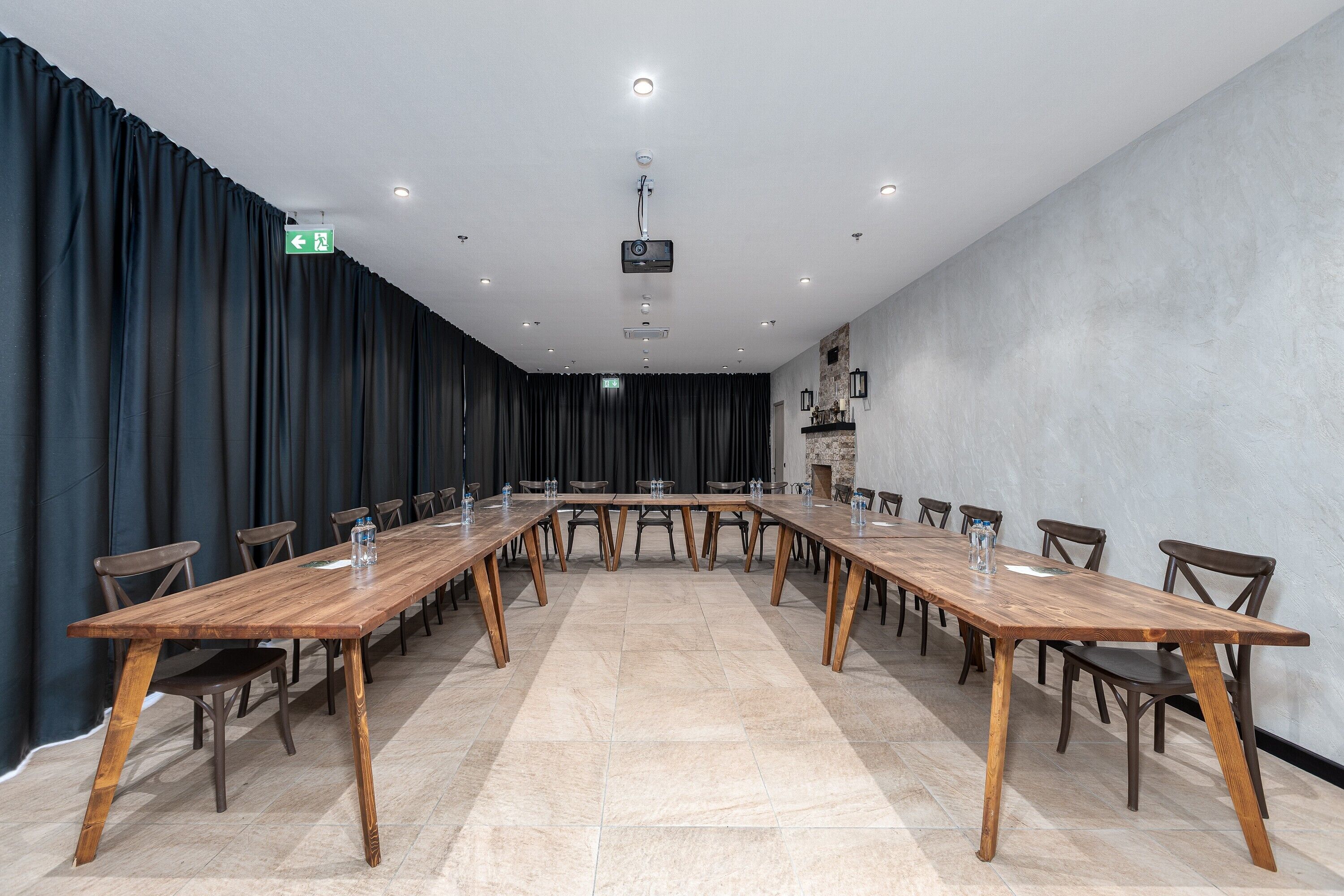 Un salón de conferencias con una larga mesa de madera, sillas y un proyector en el techo.
