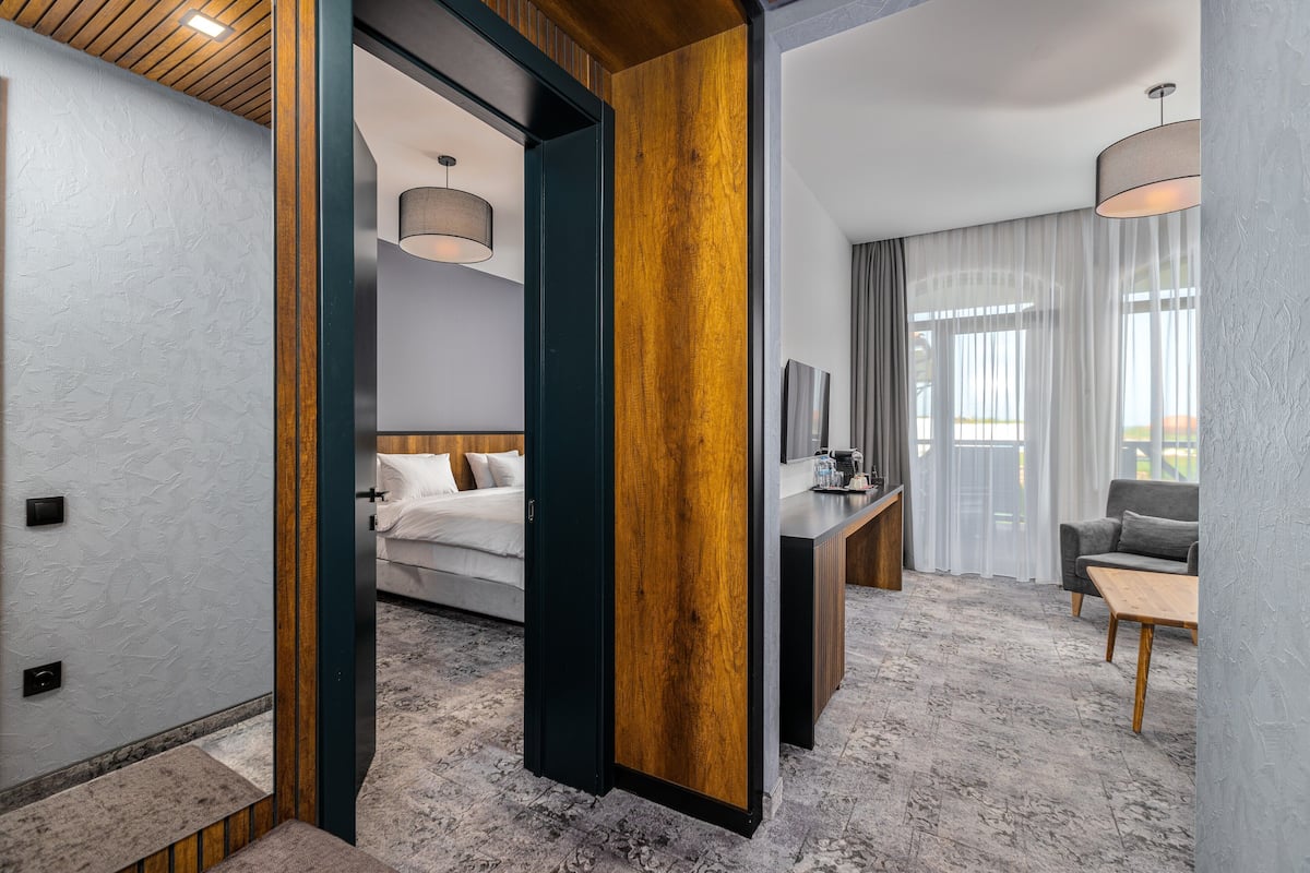 A modern hotel room with a bed, a desk, a chair, and a sofa.