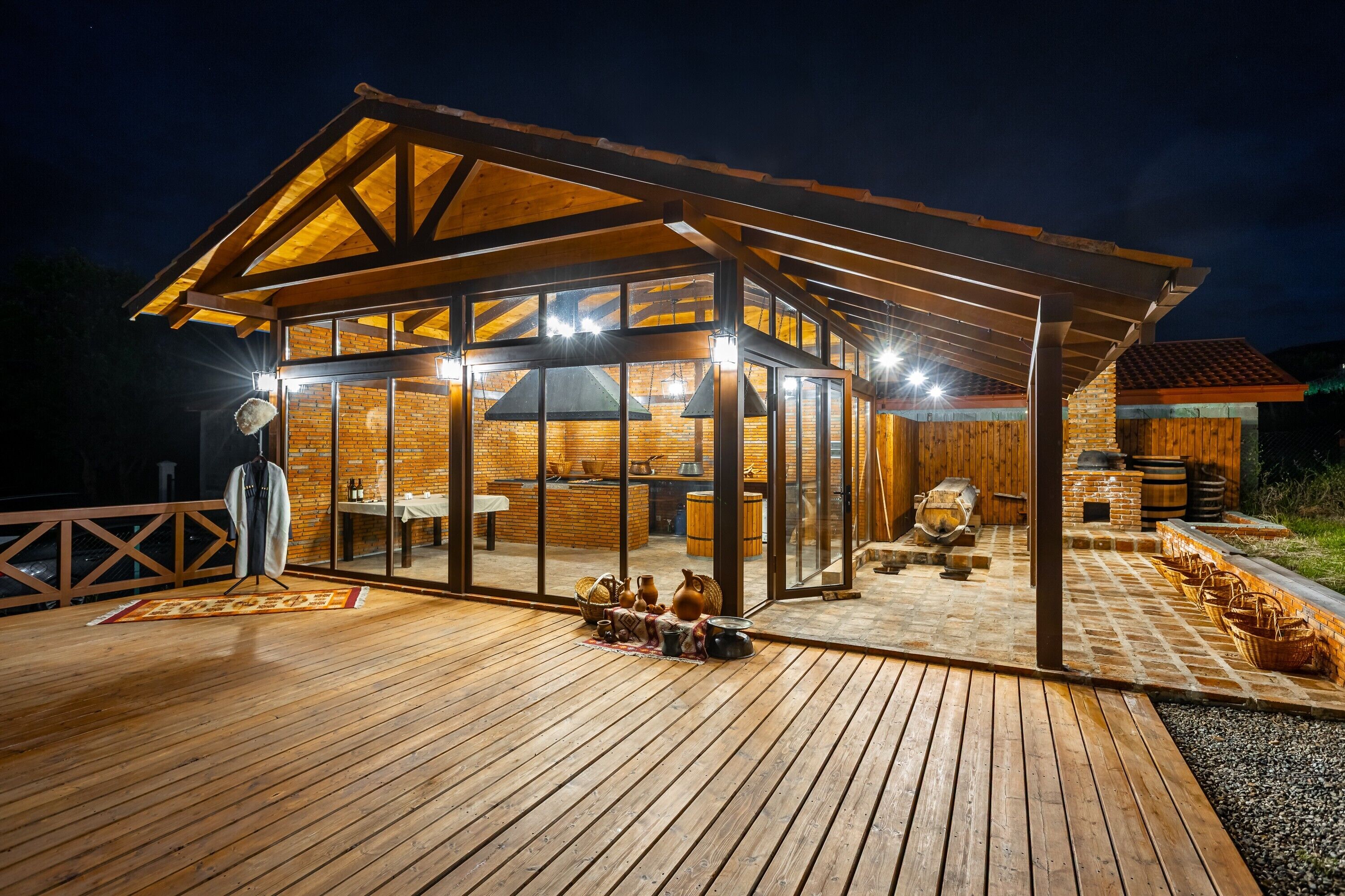 A wooden deck with a glass-enclosed patio area, a brick fireplace, and a stone-tiled floor.