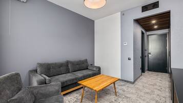 A modern living room with a grey sofa, a wooden coffee table, and a grey armchair.