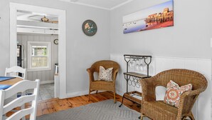 Un coin repas avec des chaises en osier, une table et un porte-bouteilles fixé au mur.