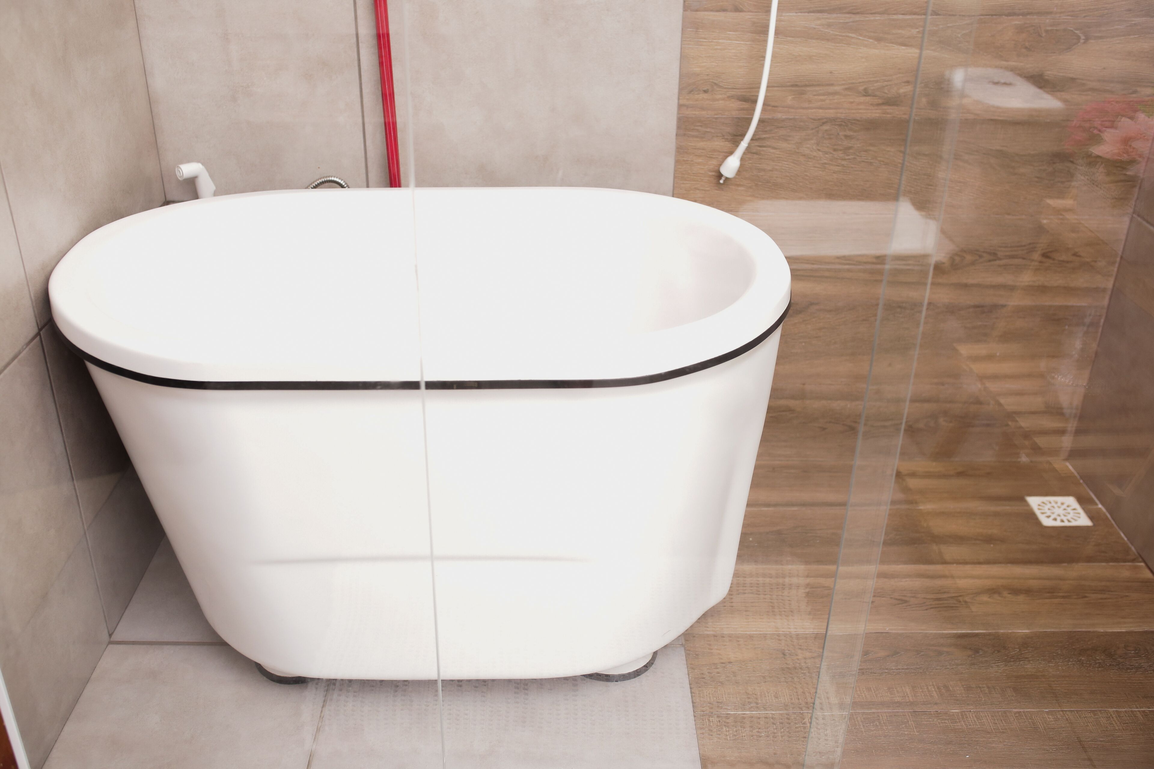 A modern bathroom with a freestanding bathtub, tiled walls, and a wooden floor.