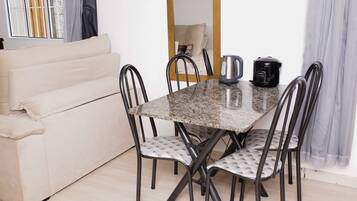 Un coin repas comprenant une table en marbre, quatre chaises rembourrées, un canapé, une bouilloire et une machine à café.