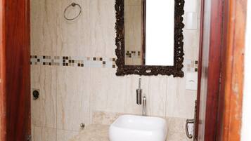 A bathroom with a white sink, a mirror with an ornate frame, and a tiled backsplash.