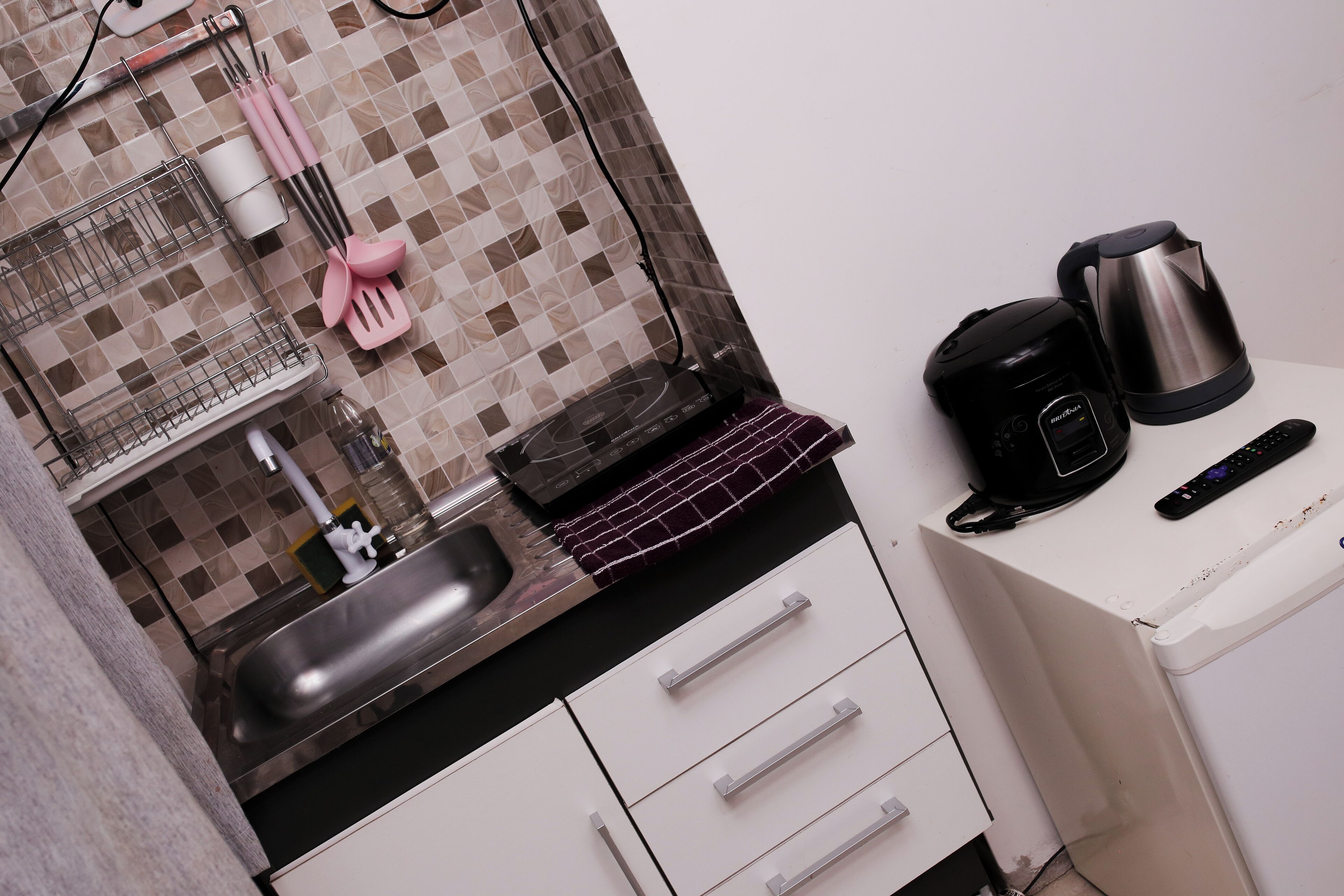 A kitchenette with a sink, a kettle, a coffee maker, and a microwave.