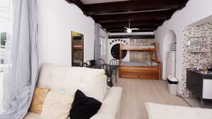 A compact room with a white sofa, a bunk bed, a small kitchen area, and a bathroom. - Castelinho Solemar - Hot Spa (Praia Grande)