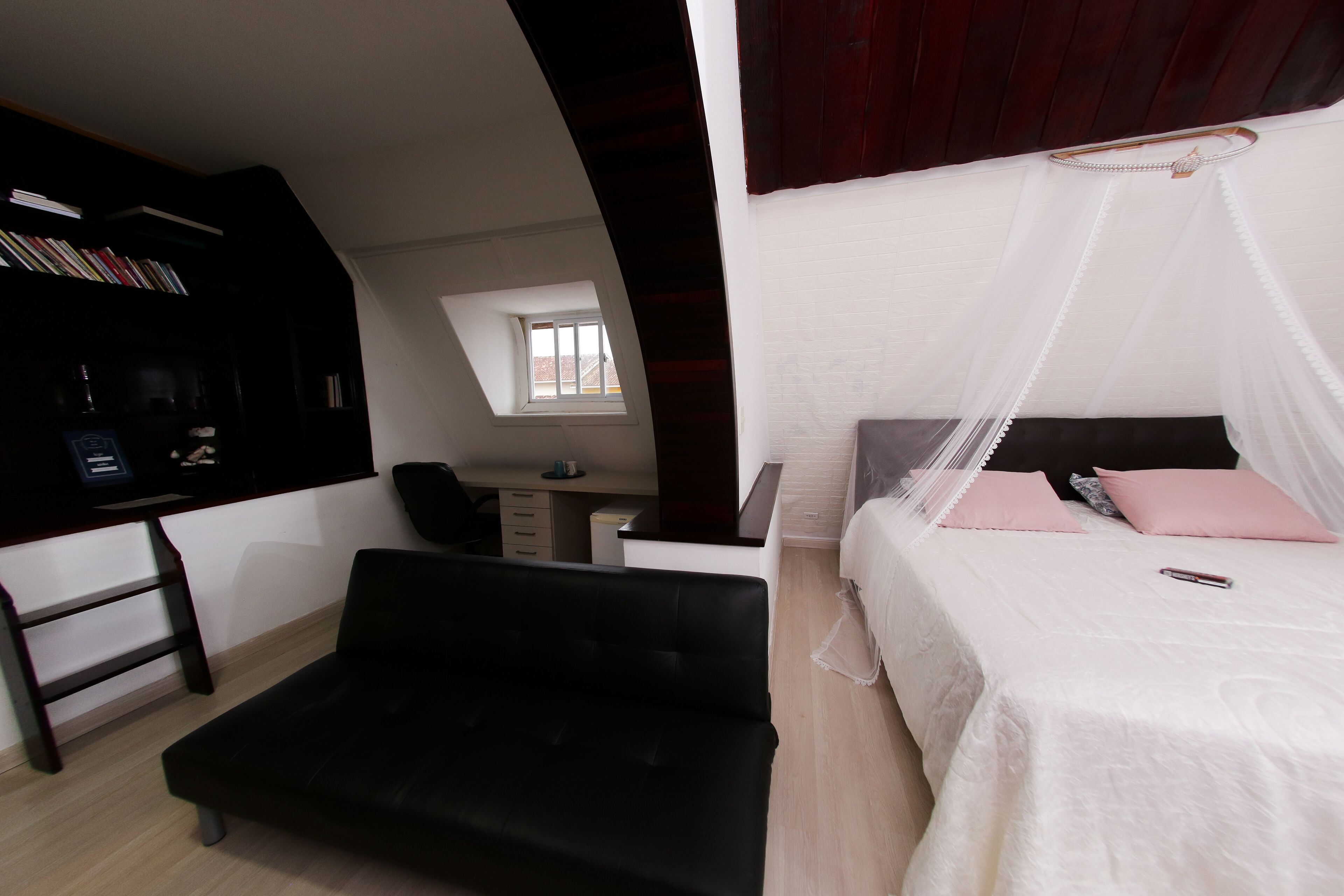 Un dormitorio con cama, escritorio y estantería.