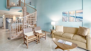 A spacious living area with a spiral staircase, a sofa, chairs, and a coffee table. - Kamaole Sands 1-403 - Ultimate getaway!  Spacious 2/2 with split AC, Large Lanai (Kihei)