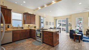 A spacious kitchen with wooden cabinets, a built-in oven, and a large island. - Mission Paradise - Spa, Pet Friendly, Steps to Sand & W/D! (Mission Beach)