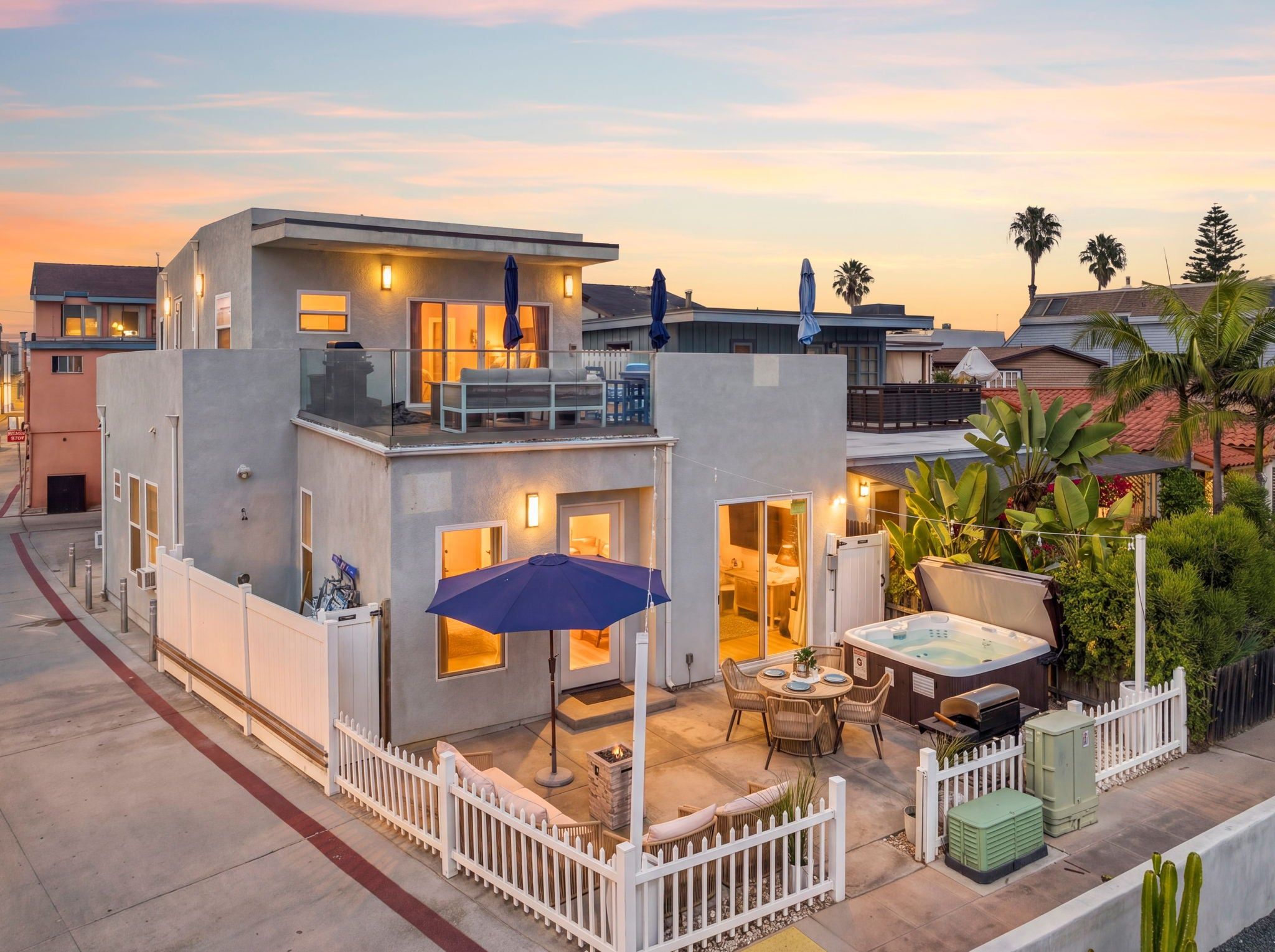 A modern two-story house with a balcony, outdoor seating, and a hot tub.