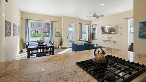 A modern kitchen with granite countertops, a gas stove, and a dining area with a table and chairs. - Mission Paradise - Spa, Pet Friendly, Steps to Sand & W/D! (Mission Beach)
