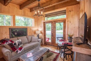 A cozy cabin interior with a sofa, coffee table, and dining area.