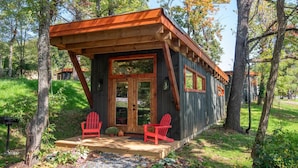 A cabin with a wooden exterior, a porch with two red Adirondack chairs, and a door with the number 1106.