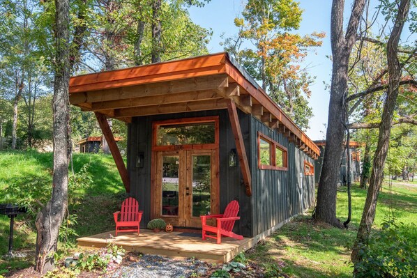 A cabin with a wooden exterior, a porch with two red Adirondack chairs, and a door with the number 1106.