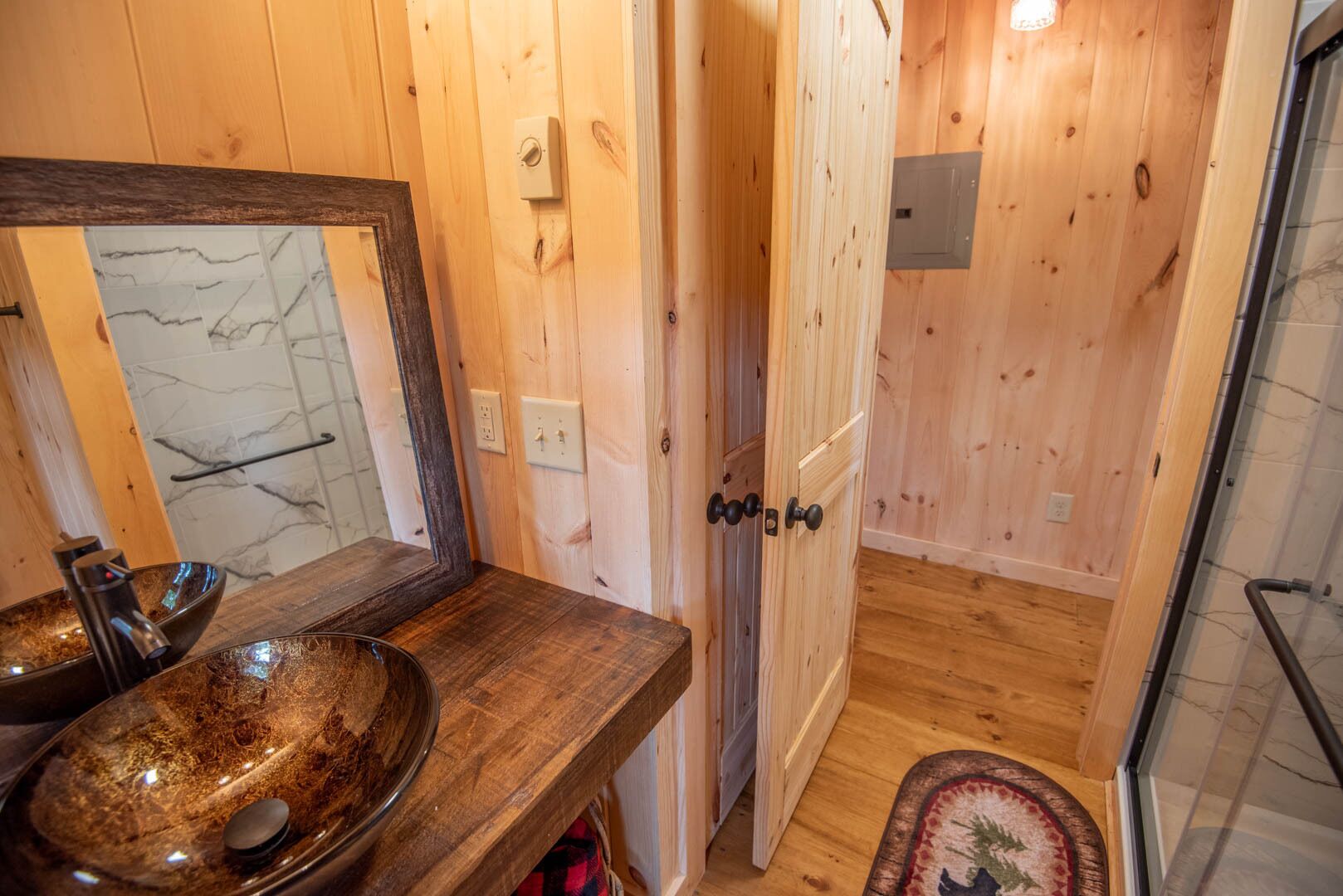 Une salle de bain en bois avec un grand miroir, un lavabo en bois et un espace douche.