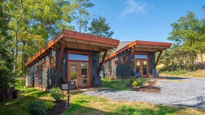 Ein rustikales Holzhaus mit großen Fenstern und einer Zuwegung mit Kies.