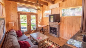 Ein Holzblockbau-Innenraum mit Sofa, Tisch, Kamin, Fernseher und Essbereich.