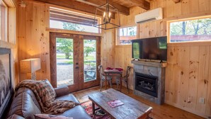 A cozy cabin interior with a sofa, fireplace, television, and wooden walls.