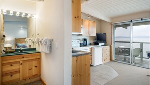 A modern kitchen with wooden cabinets, a sink, and a large window overlooking a balcony. - Flathead Lake Waterfront Studio! (Bigfork)