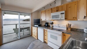 A modern kitchen with wooden cabinets, a microwave, stove, and a large window overlooking a body of water.