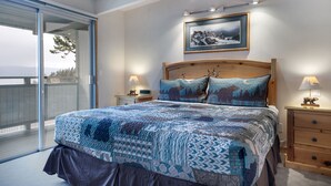 Ein Schlafzimmer mit einem großen Bett, einem Holzkopfteil, einem Gemälde über dem Bett und einem Nachttisch mit Lampe.