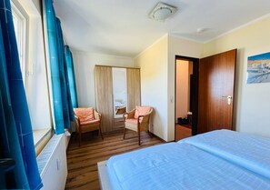 Una camera d'albergo con un letto, una sedia, un armadio e una finestra con tende.