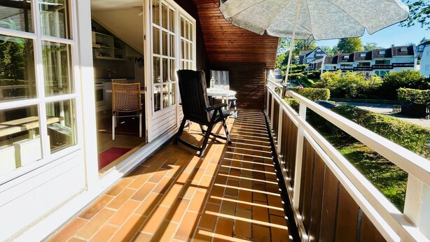 A balcony with a wooden ceiling, a table with chairs, and a view of a residential area.