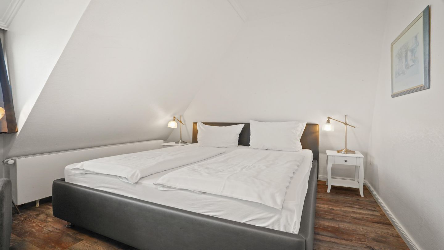 Une chambre à coucher avec un lit, deux tables de chevet et une commode.