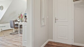 Een modern interieur met een eethoek, een witte deur en een hangende kapstok.