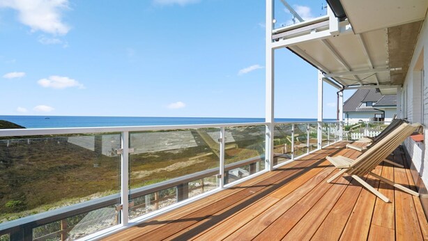 A wooden deck with a glass balustrade overlooking a beach. - Käpitäns-suite - Haus Seeblick (Hörnum (Sylt))