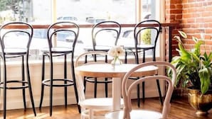 A cafe with a brick wall, large windows, and wooden flooring. - The Bishop Hotel (Port Townsend)