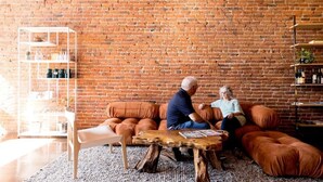 A cozy living room with a brick wall, a white shelving unit, and a wooden coffee table. - The Bishop Hotel (Port Townsend)
