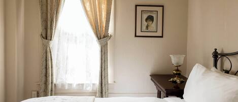 Una habitación de hotel con una cama, una mesita de noche, una lámpara y un cuadro en la pared.