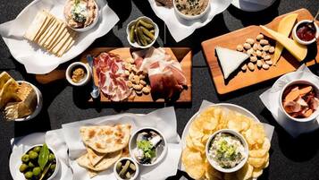 Una variedad de alimentos como carnes, quesos, aceitunas y papas fritas, dispuestas sobre una mesa.