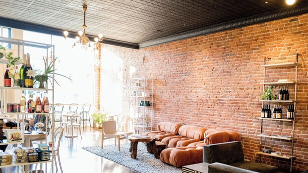 A modern interior with a brick wall, leather sofa, and shelves with bottles. - The Bishop Hotel (Port Townsend)