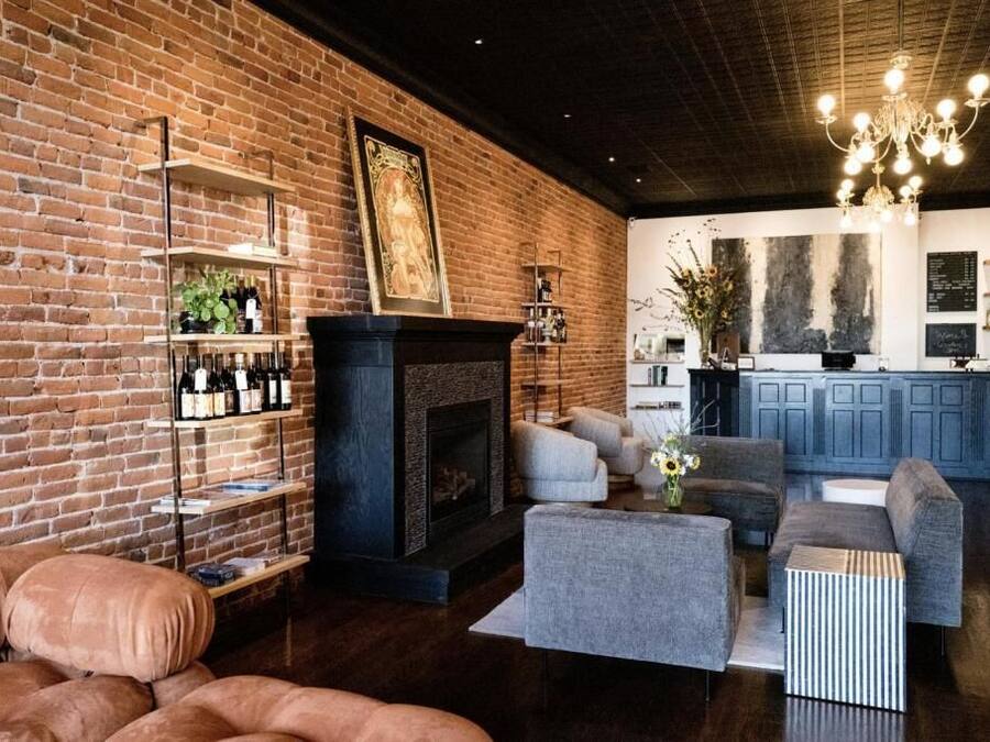 A cozy living room with a brick wall, a fireplace, and a modern kitchen in the background.