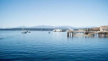 A calm waterfront with boats, a pier, and distant mountains.