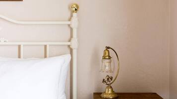 A bed with a white headboard and a bedside table with a brass lamp.