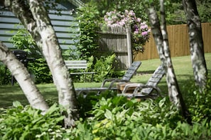Relax in a serene garden setting with a seating area featuring two lounge chairs and a table.