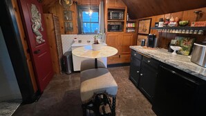 Cocina compacta con gabinetes de madera, microondas y cafetera.