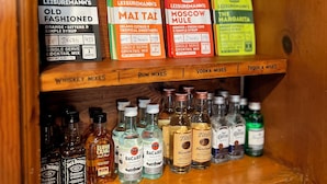 Una estantería con varias botellas de licor y cajas de mezcladores para cócteles.
