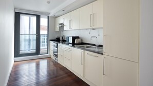 Una cocina moderna con un ventanal grande, piso de madera y armarios blancos.