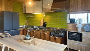 Una cocina moderna con armarios de madera, estufa de acero inoxidable y salpicadero de azulejos verdes.