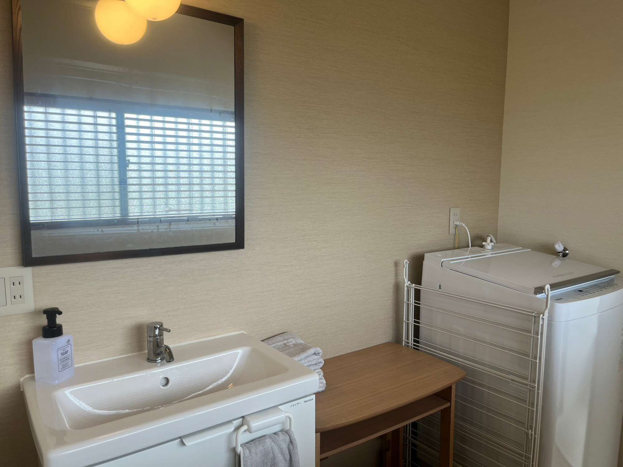 A bathroom with a sink, mirror, and a drying rack.
