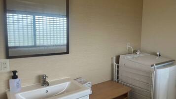 A bathroom with a sink, mirror, and a drying rack.