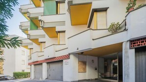 A multi-story building with a flat facade, large windows, and a parking area in front.