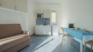 A compact living space with a kitchenette, a dining area, and a sofa.