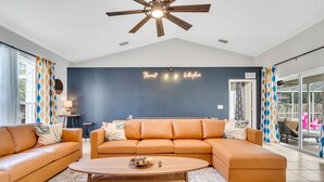 A modern living room with a sectional sofa, a coffee table, and a ceiling fan.