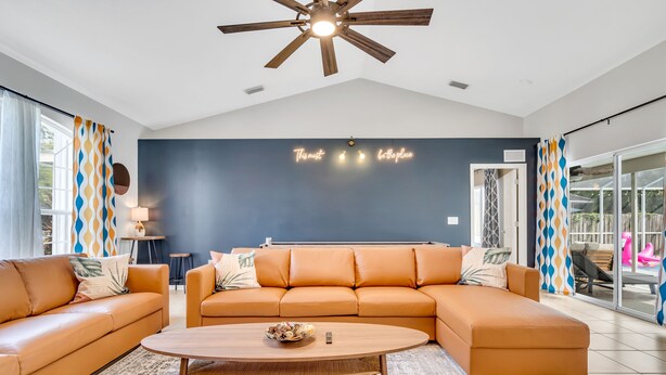 Una sala moderna con un sofá modular, una mesa de centro y un ventilador de techo.
