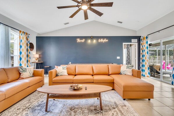 A modern living room with a sectional sofa, a coffee table, and a ceiling fan. - Free Heated Pool, Baby Gear, Shuffleboard, EV charger, Near beach, UTC mall, SRQ (Sarasota)